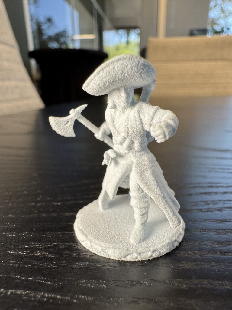 Fresh out of MJF in PA12 White. The textured powder surface and crisp detail in the hat brim, blade, and clothing folds are all original to the print.