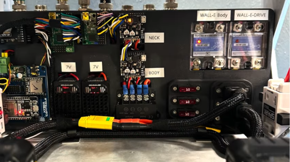 Wall-E's internal electronics panel with labeled solid-state relays for body and drive, dual 7V buck converters, fuse block, and a cleanly routed wiring harness